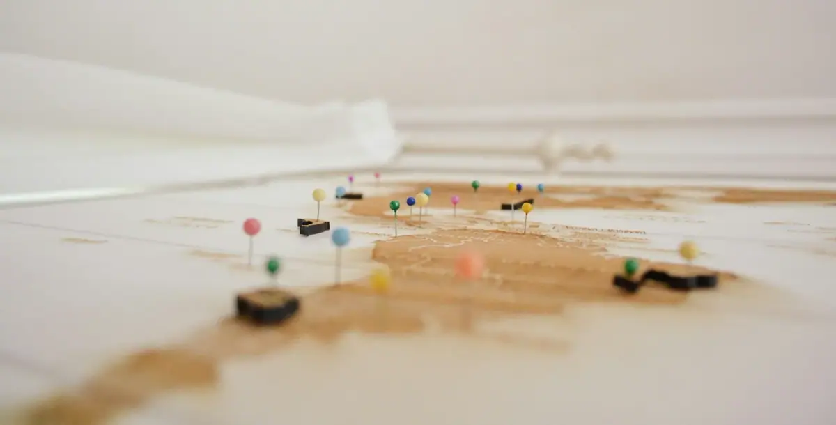 Close-up view of a vintage map with colorful push pins marking various locations.