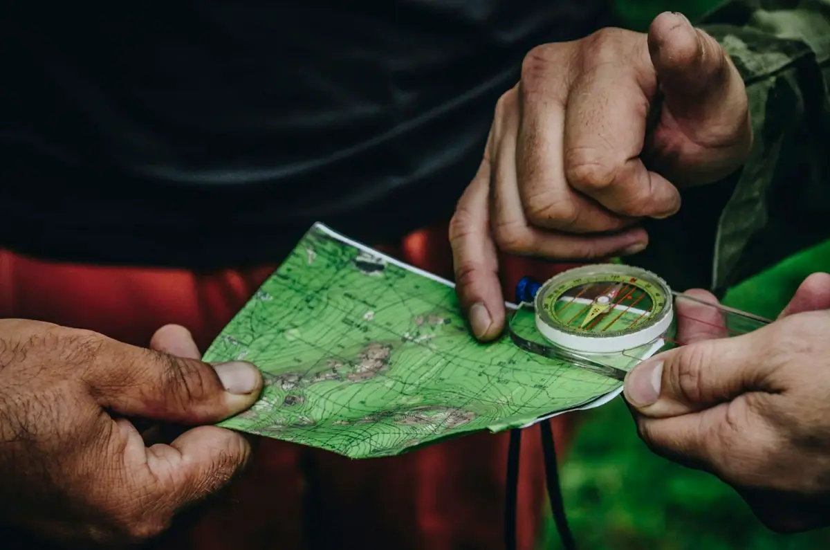 Two people holding a topographic map and a compass during outdoor navigation.