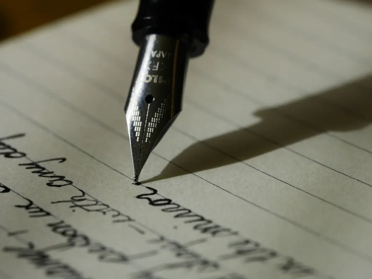Close-up of a fountain pen writing on lined paper.